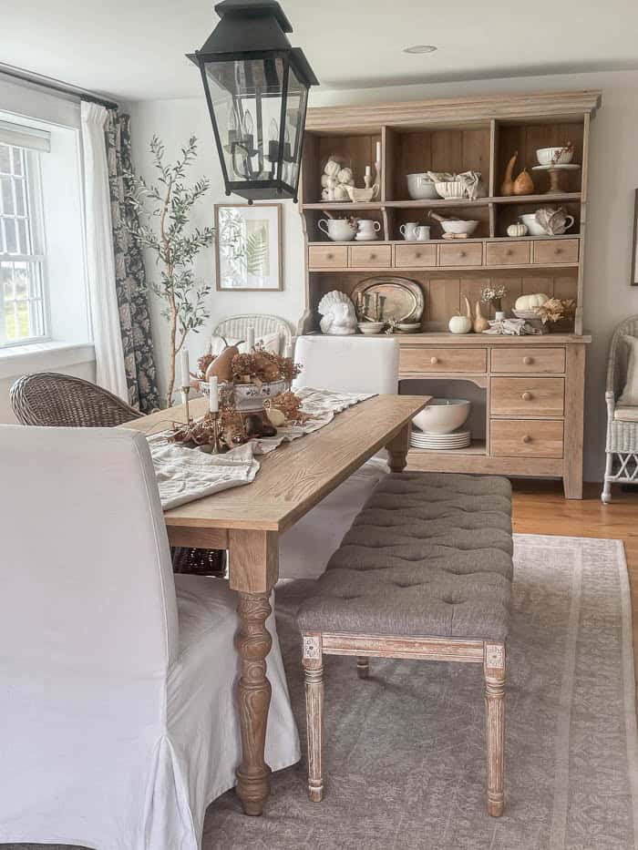 Farmhouse dining room with neutral fall table decor and wood hutch