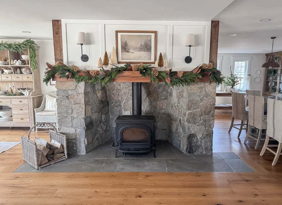 Neutral Christmas fireplace mantel with greenery garland, bottle brush trees, and stone surround