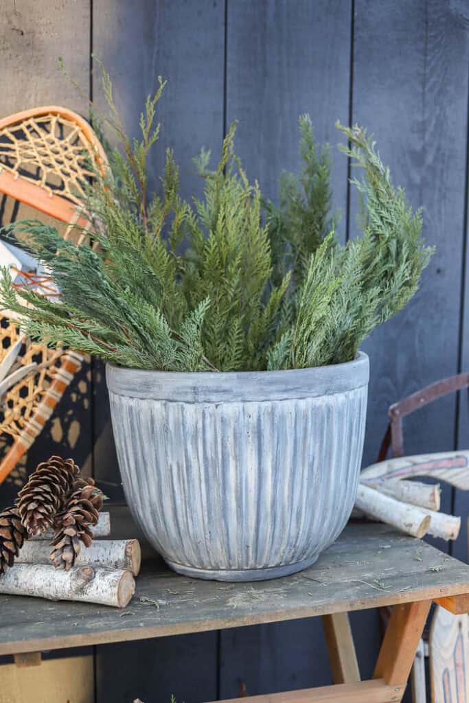 Close-up of evergreen branches, pinecones, and frosted berry stems in a winter planter.
