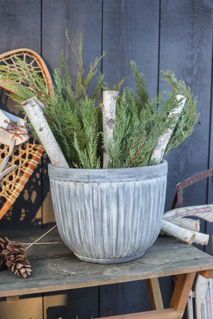 Close-up of evergreen branches, pinecones, and frosted berry stems in a winter planter.