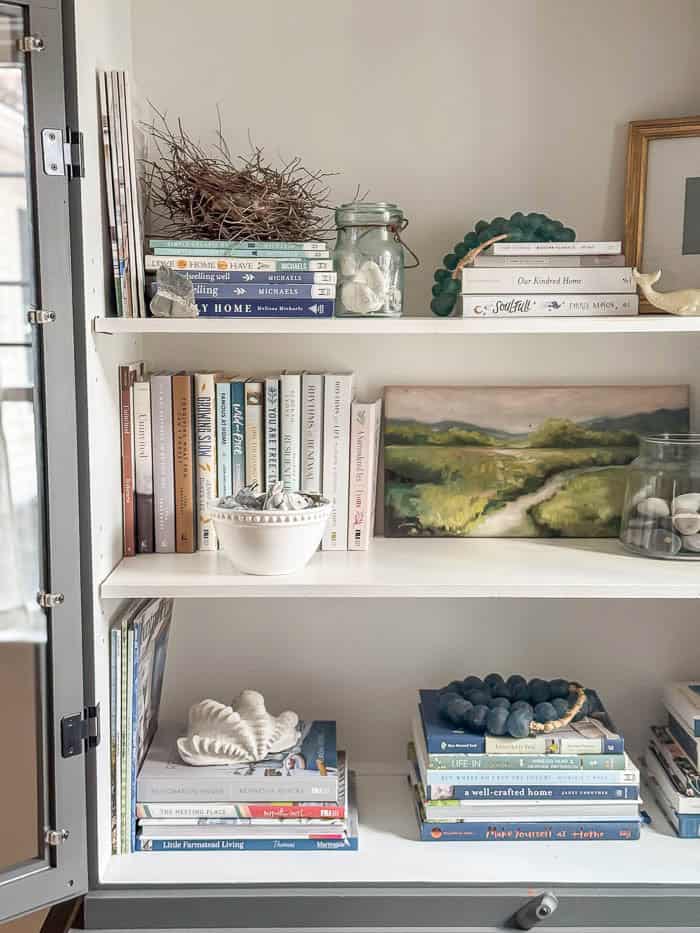 Painted hutch styled with books and seashells, traditional New England Home