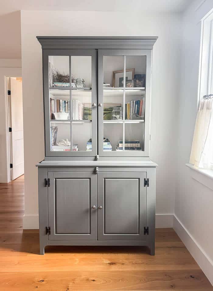 Painted gray hutch in an upstairs hallway, refinished Facebook Marketplace furniture styled with books and decor in a neutral home.