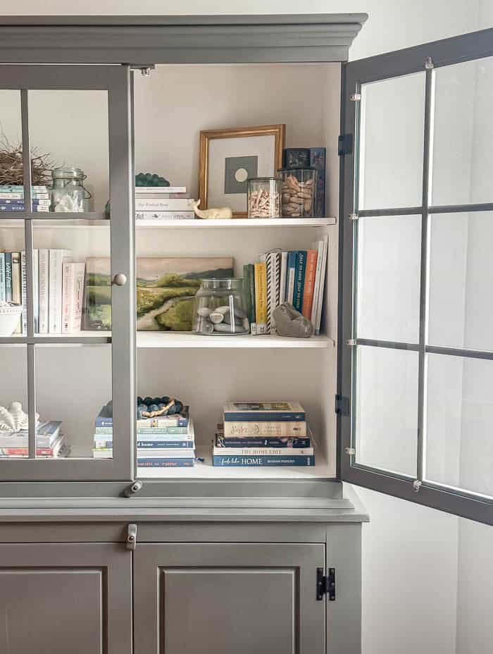 Painted hutch styled with books and seashells, traditional New England Home