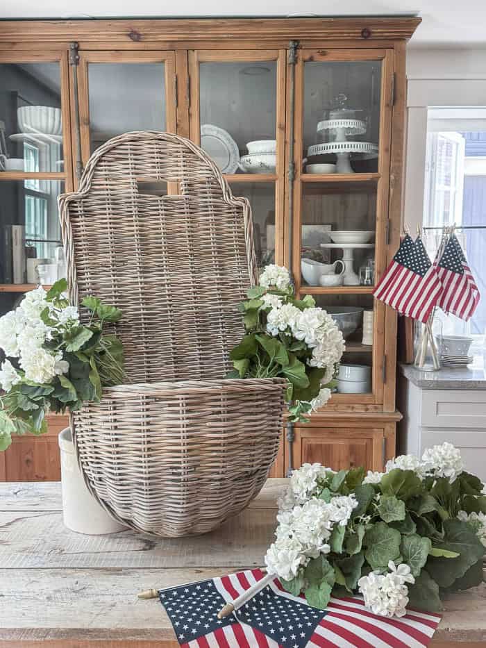 Arranging faux white geranium stems inside a wicker hanging basket using chicken wire as floral support.