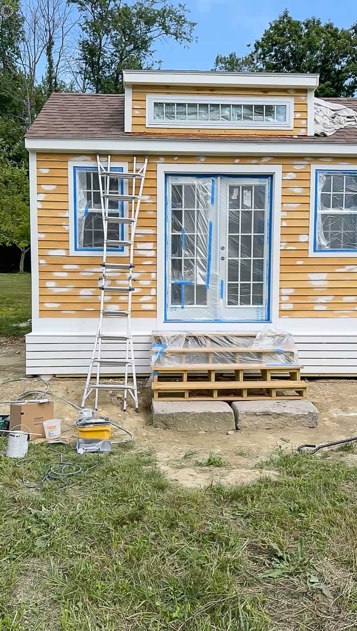 Garden shed with windows masked and wood knots primed before exterior painting